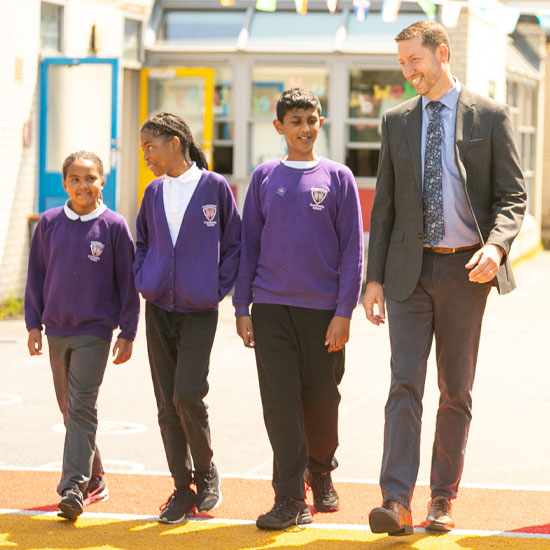 Three pupils and the headteach, Mr Reeves, walking and smiling